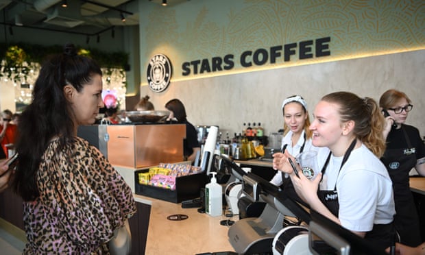 Un client parle à un barista au comptoir d'un café Stars, dont le décor rappelle beaucoup la chaîne américaine Starbucks.